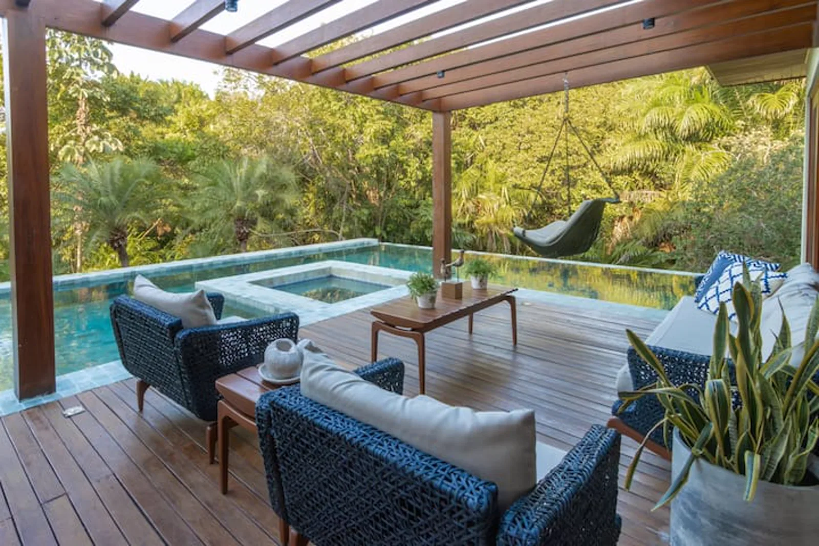 Lounge coberto e piscina de borda infinita na luz dourada do fim de tarde